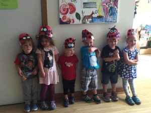 Row of smiling children with handmade ladybug hats